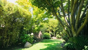Een weelderige tuin met verschillende bomen en struiken, een verzorgd gazon en een pad van stenen.