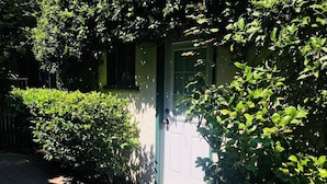Een huis met een groene deur, een pad van bakstenen en omliggende begroeiing.