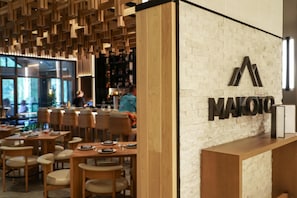 Ein modernes Restaurant mit Holztischen, einer Ziegelwand und einer sichtbaren Bar.