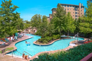 A swimming pool with multiple lanes, surrounded by trees and lounge chairs.