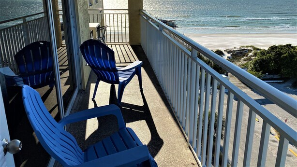 A balcony with two blue chairs and a table, overlooking a beach with a railing. - Fantastic Gulf View! On the beach! 3 Bdrms, 3 Baths, Great Pool and Hot Tub (Redington Shores)