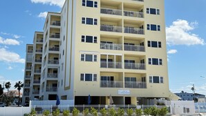 A multi-story hotel with balconies, a sandy beach in front, and a clear blue sky. - Fantastic Gulf View! On the beach! 3 Bdrms, 3 Baths, Great Pool and Hot Tub (Redington Shores)
