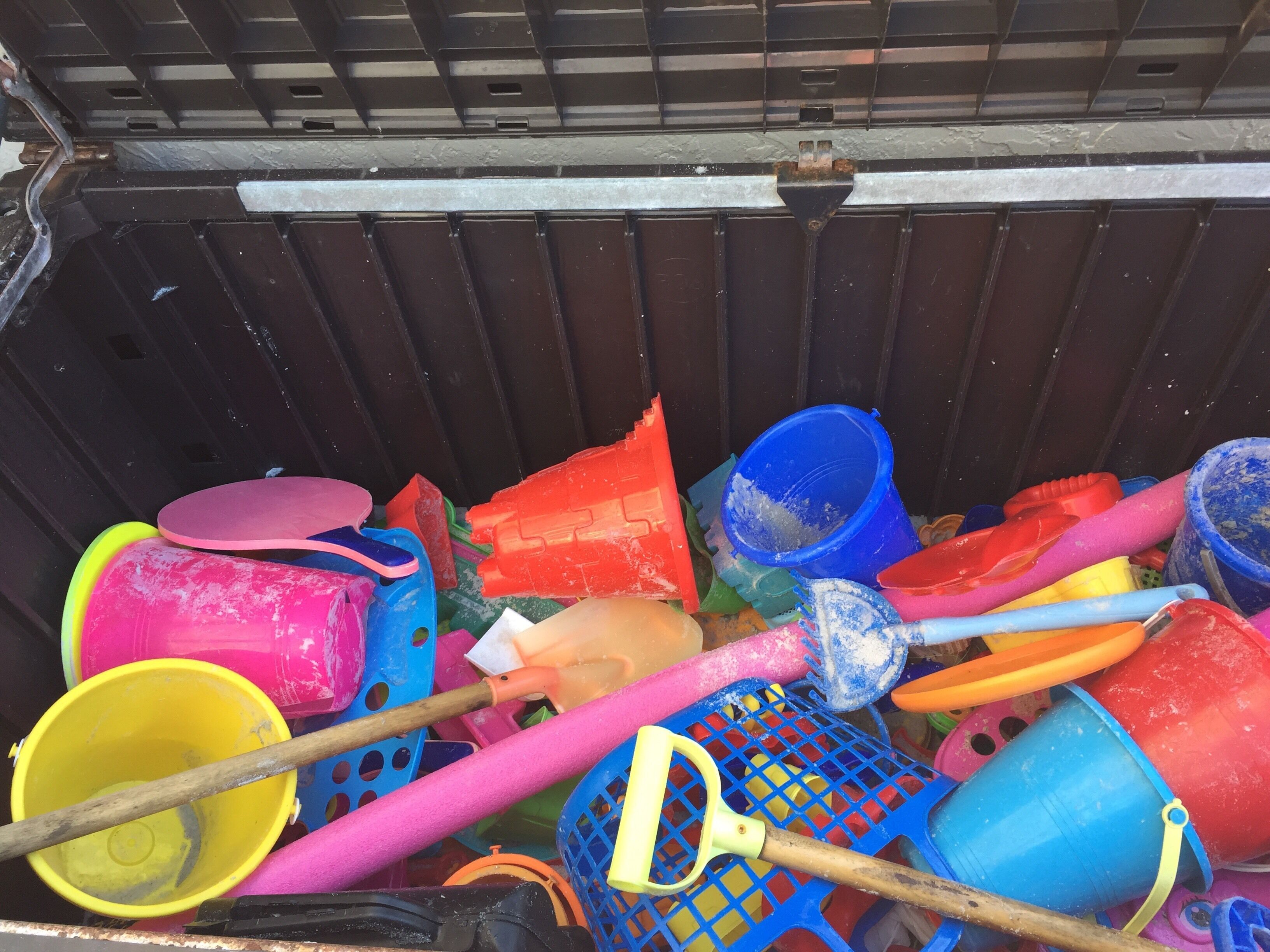 A collection of colorful plastic beach toys and buckets in a storage area.