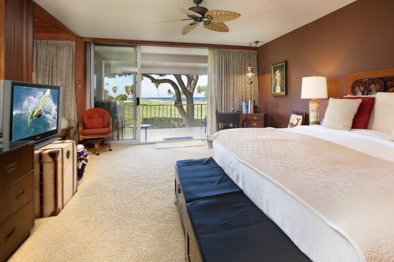 Habitación de hotel con una cama grande, televisión, escritorio y vistas al exterior.