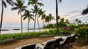 A beachside lounge with wicker chairs and a view of the ocean.