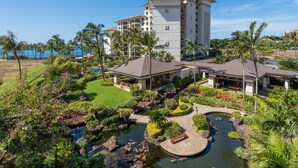 A resort with a large building, a landscaped garden, and a pond with koi fish.