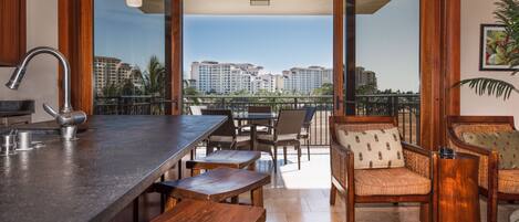 Une cuisine moderne avec un coin bar, des meubles en bois et une vue sur le paysage urbain, visible à travers de grandes portes vitrées.