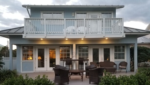 Une maison à deux étages dotée d’un balcon, d’un espace extérieur aménagé pour s’asseoir et d’une terrasse couverte.
