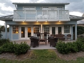 Ein zweistöckiges Haus mit Balkon, Sitzgelegenheit im Freien und überdachter Terrasse.