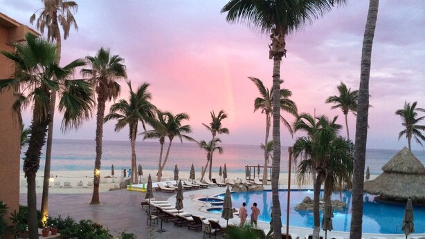 A resort pool area with palm trees, lounge chairs, and a view of the ocean. - Ocean view, one bedroom, steps to the pool and beach.  Pride in ownership. (San Jose del Cabo)