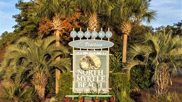 Un panneau indiquant l’entrée de North Myrtle Beach, en Caroline du Sud, entouré d’une végétation tropicale.