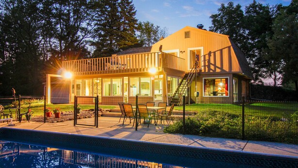 Une maison avec une piscine, une terrasse et un escalier menant à un balcon.
