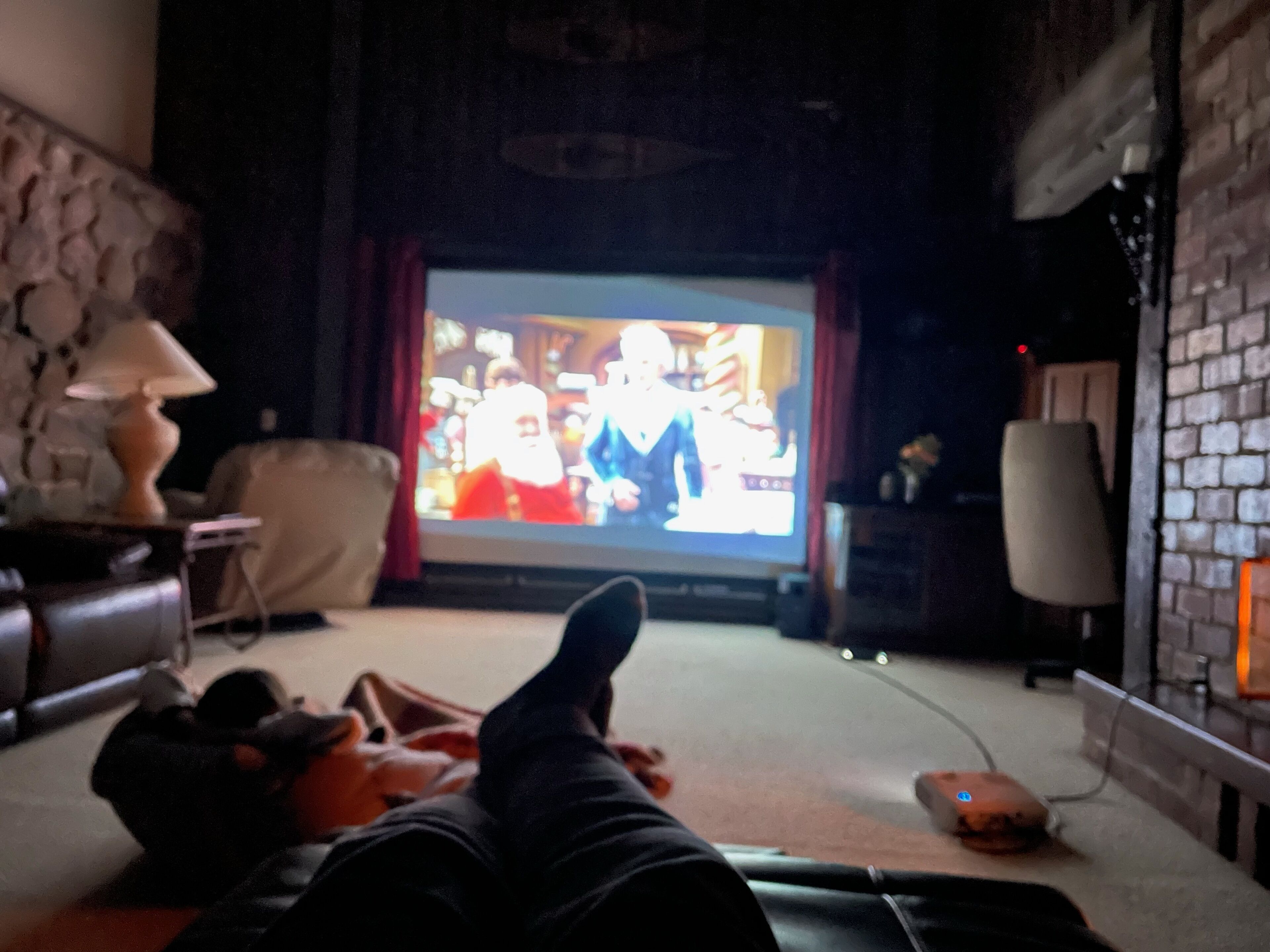 Ein Wohnzimmer mit Fernseher, einer Couch und einer Lampe.