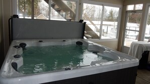 Un bain à remous avec vue sur un espace extérieur enneigé, grâce à de grandes fenêtres.