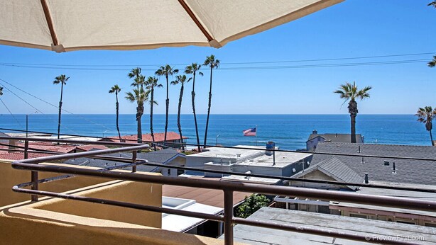 A balcony with a view of the ocean and palm trees. - OCEANSIDE BEACH located by pier and marina! Ocean Views! Walk to Village! (Oceanside)