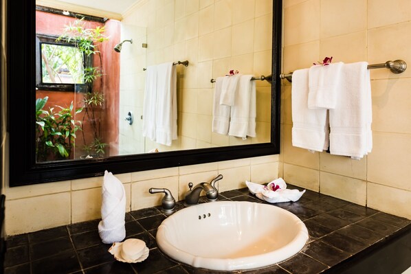 A bathroom with a large mirror, a white sink, and two towel racks with white towels.