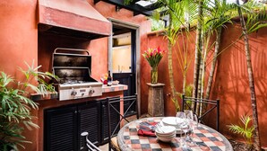 Une terrasse avec un réchaud à gaz, une table dressée pour le repas et des plantes en pot.