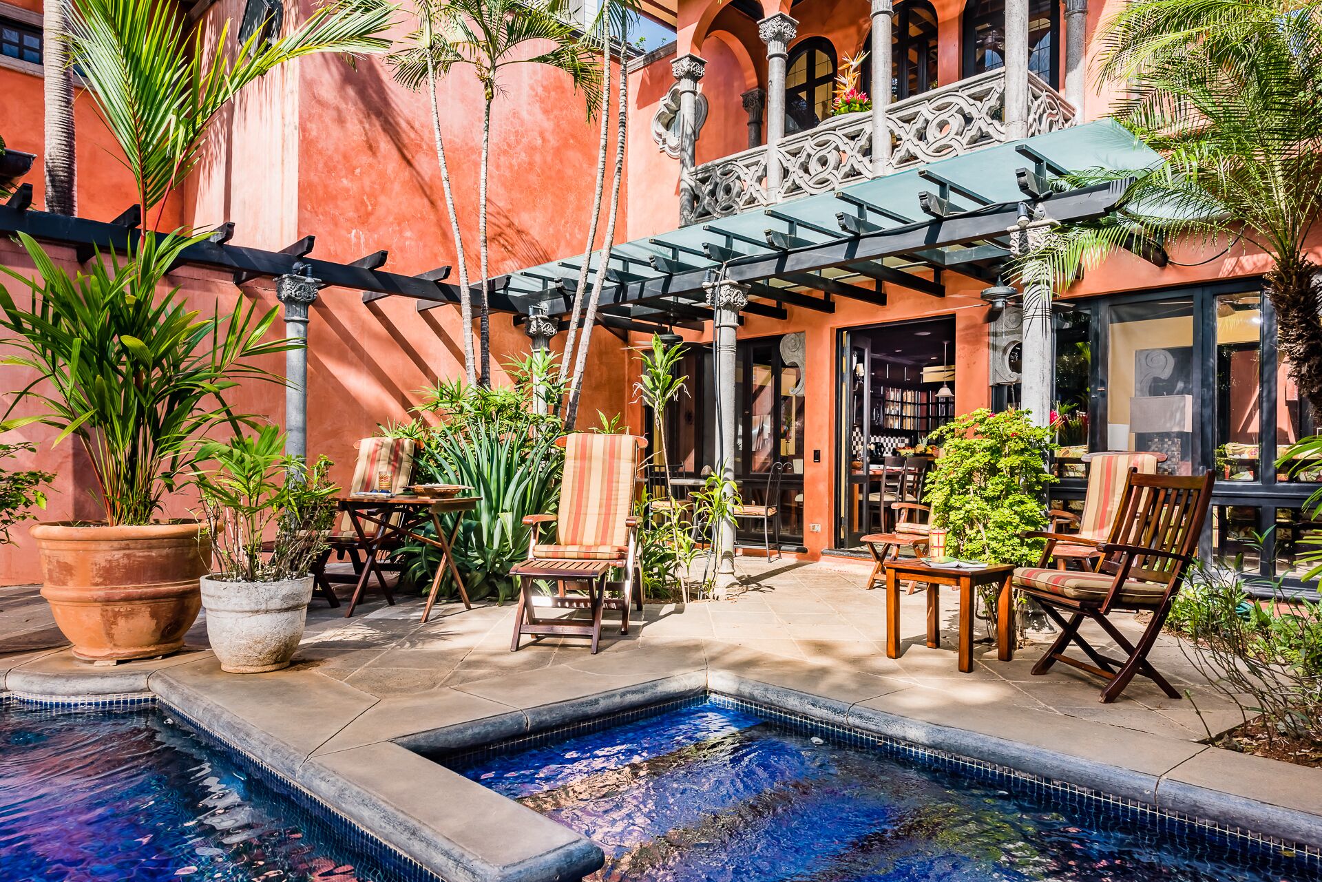 Une terrasse extérieure avec une piscine, des sièges et des plantes en pot.