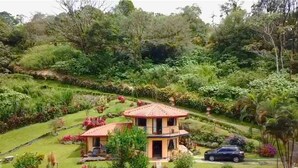 Ein Haus mit rotem Ziegeldach, umgeben von üppiger Vegetation und einem gepflegten Garten.