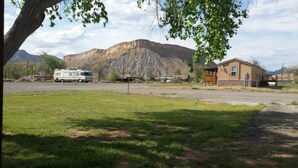 A campground with a large RV, a small building, and a mountain in the background. - Catalina Park Model, in RV Ballard RV Park  (Thompson)