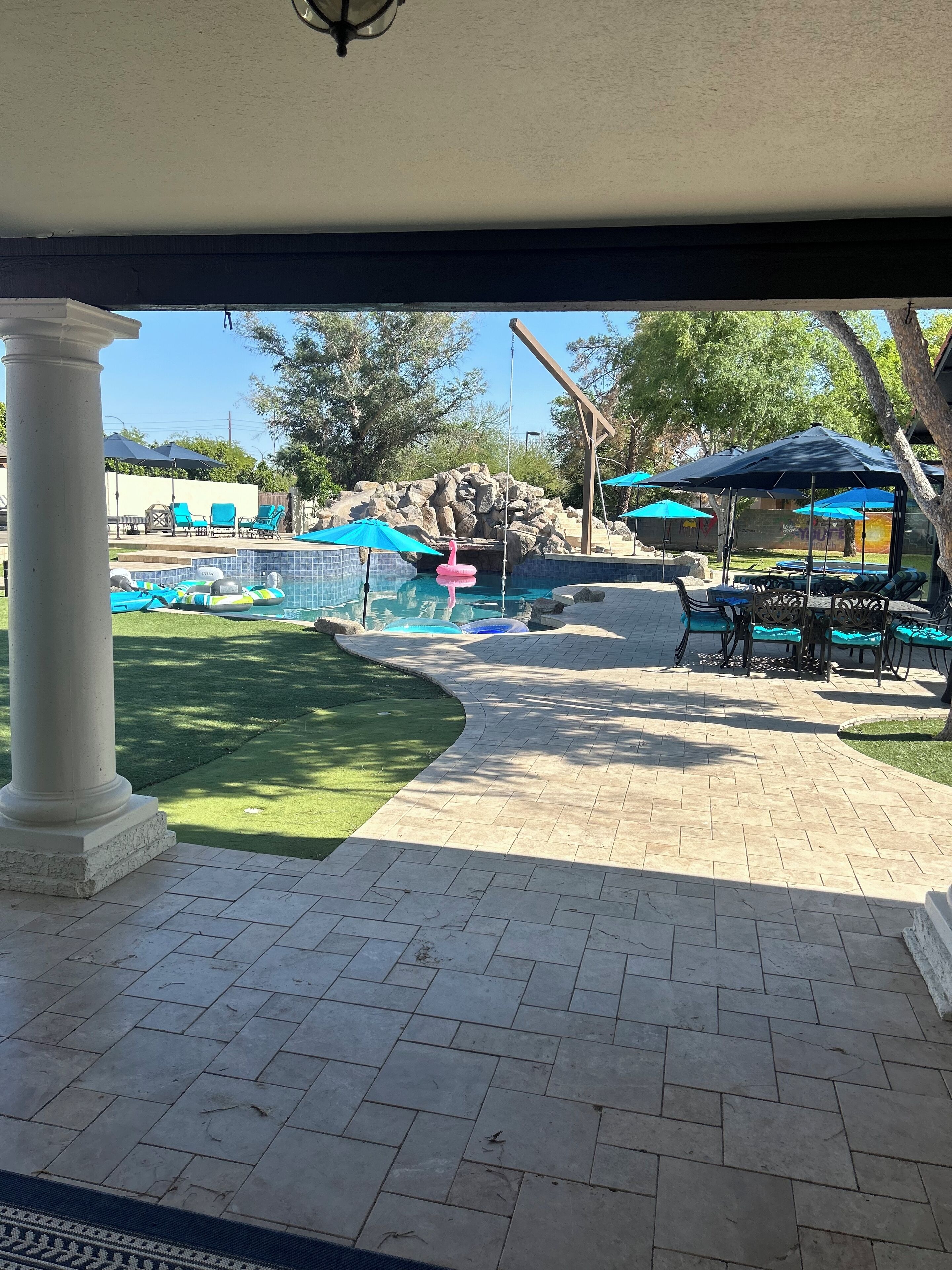 Zona de piscina amb mur de pedra, gandules i ombrelles.