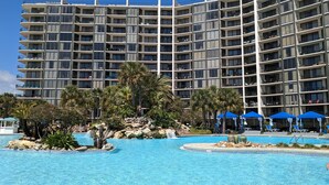 A multi-story hotel with balconies, a swimming pool, and palm trees. - Spectacular 3rd floor Pool and Beach Views (Panama City Beach)