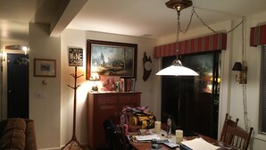 A dining area with a wooden table, chairs, a lamp, and a painting on the wall. - Pine Creek Treehouse (Gaines)