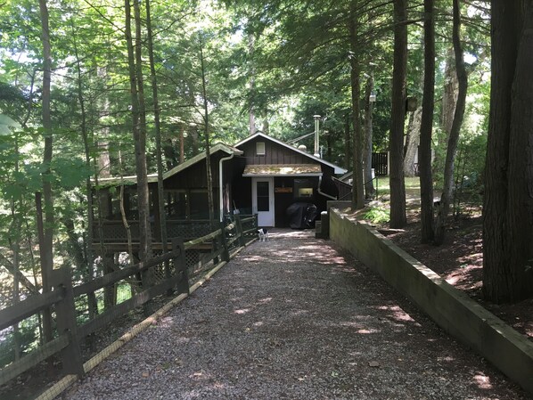 A wooden cabin with a covered porch, surrounded by trees.