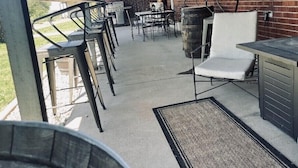 An outdoor patio area with metal chairs and tables, a brick wall, and a large window. - LUXE Lodge 80ac. Huge pond cattle Ranch Views Close Nat Parks Ski McPhee (Dolores)