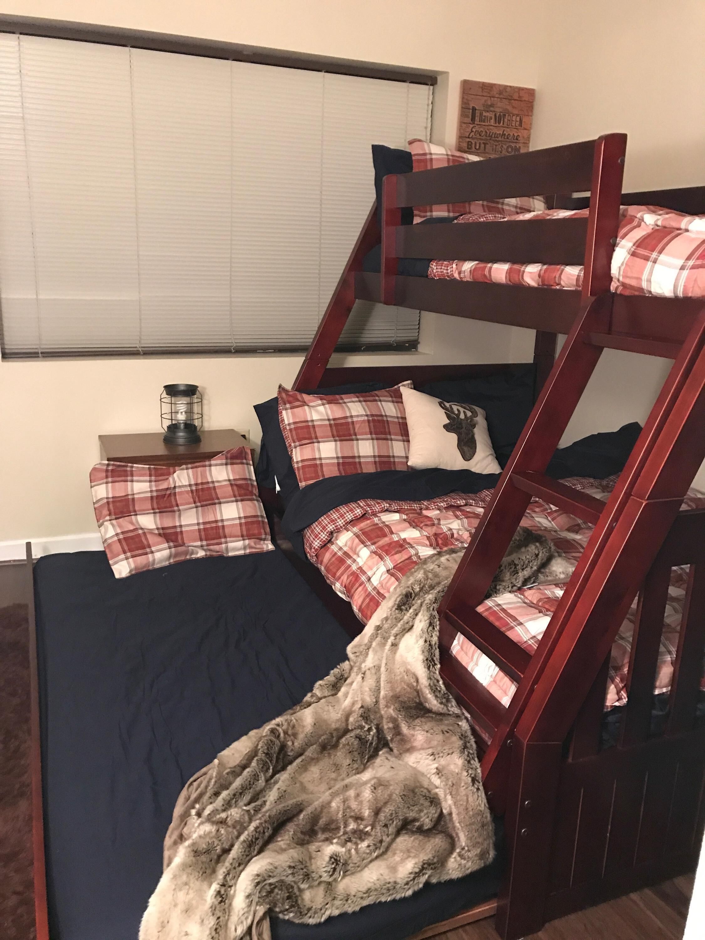 A bunk bed with plaid bedding and a fur throw.