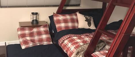A bunk bed with plaid bedding and a fur throw.