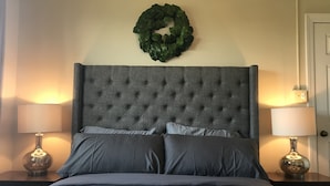 A bed with a tufted headboard, two bedside lamps, and a green wreath on the wall. - Spectacular Mile High View,Free Wifi-Pool-Smart Tvs-W&D-Gym-No hidden fees ! (Banner Elk)