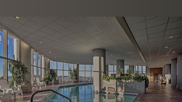 An indoor swimming pool with clear glass walls, a tiled floor, and a few lounge chairs. - Spectacular Mile High View,Free Wifi-Pool-Smart Tvs-W&D-Gym-No hidden fees ! (Banner Elk)