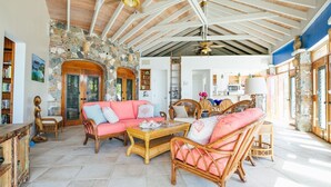A spacious living room with a stone wall, wooden ceiling beams, and a large window.