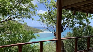 A wooden deck with a view of a coastal landscape, including a beach and ocean.