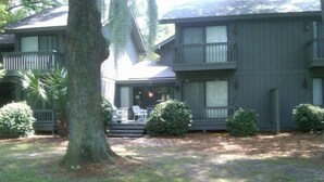 Ein zweistöckiges Haus mit Veranda, einem großen Baum und einem gepflegten Rasen.