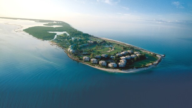 An aerial view of a coastal resort with multiple buildings, a golf course, and a beach. - Villa Salva, Your Home Away From Home! (Cape Coral)