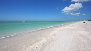 A beach with clear turquoise waters, a boat in the distance, and a few people on the sand. - Villa Salva, Your Home Away From Home! (Cape Coral)