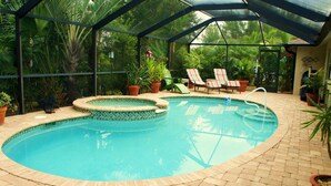 A swimming pool with a hot tub, surrounded by potted plants and lounge chairs. - Villa Salva, Your Home Away From Home! (Cape Coral)