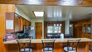 A wooden kitchen with a bar area, including a refrigerator, stove, and bar stools. - COZY CABIN IN COUNTRY CLUB WITH FOREST VIEWS-PETS WELCOME! (Pinetop)