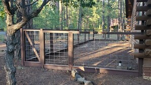 A wooden cabin with a fenced outdoor area, surrounded by trees. - COZY CABIN IN COUNTRY CLUB WITH FOREST VIEWS-PETS WELCOME! (Pinetop)