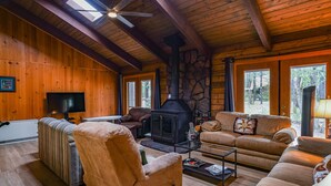 A cozy cabin interior with wooden walls, a stone fireplace, a television, and a sofa. - COZY CABIN IN COUNTRY CLUB WITH FOREST VIEWS-PETS WELCOME! (Pinetop)