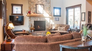 A cozy living room with a stone fireplace, leather sofa, and a television.