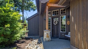 A wooden cabin with a stone entrance, a bench outside, and a wreath on the door.
