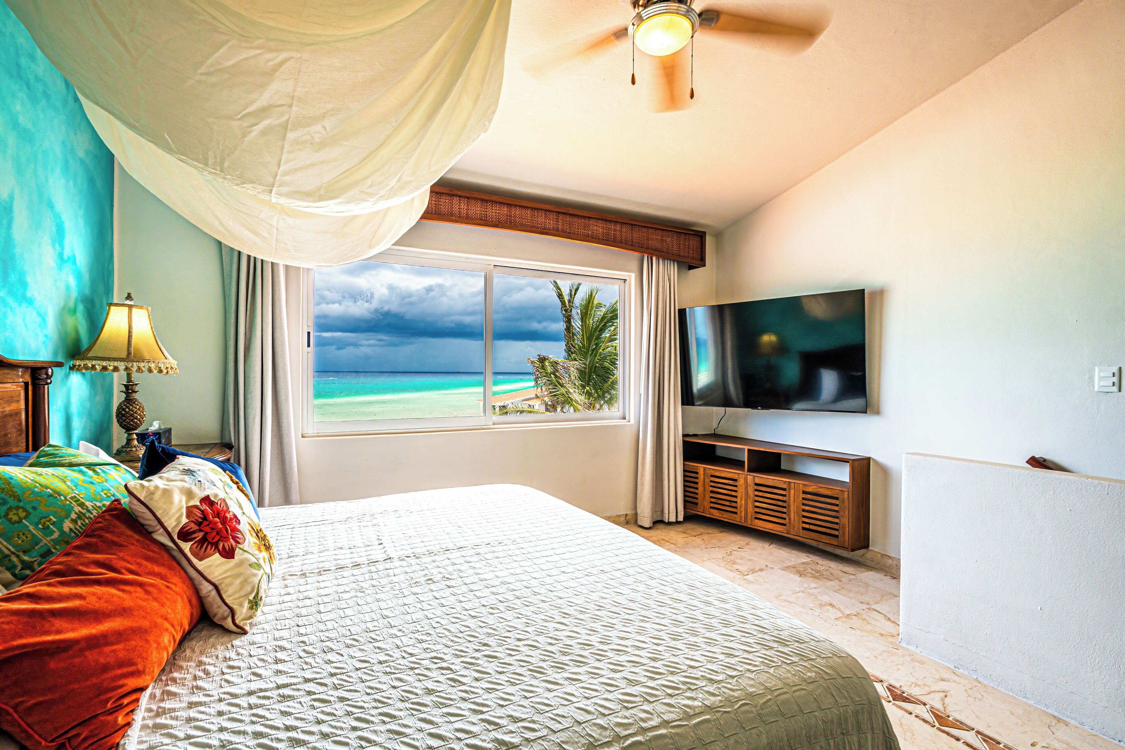 A hotel room with a large bed, a television, and a view of the ocean.