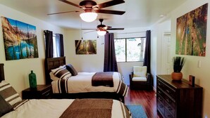 Een slaapkamer met een bed, een stoel, een dressoir en een plafondventilator.