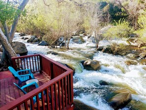 A wooden deck with blue chairs overlooking a flowing river with rocks and trees. -  "River Retreat House" - River With Two Decks, BBQ, Firepit🔥, near Sequoia Park (Three Rivers)