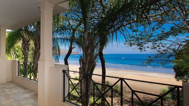 A balcony with a view of a beach and ocean.