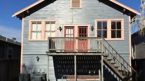 A two-story house with a front porch, a staircase leading to the upper level, and a fenced backyard.