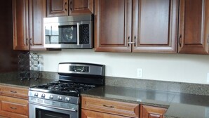 A kitchen with dark wooden cabinets, stainless steel appliances, and a granite countertop.